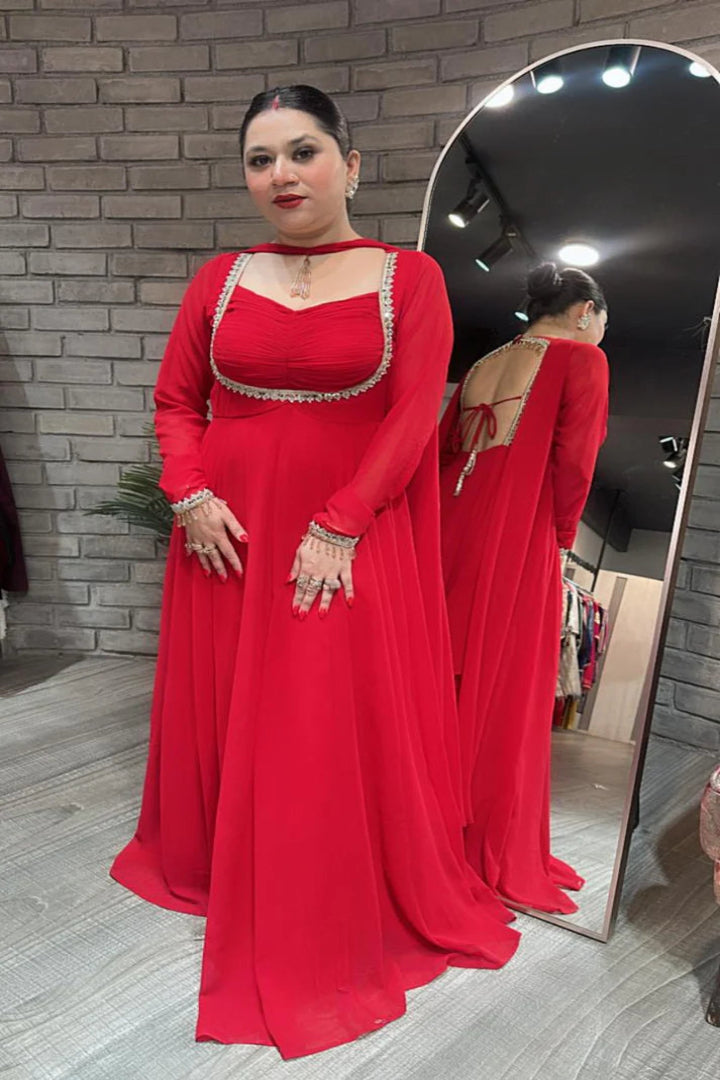 Woman in a red evening gown standing in front of a mirror.