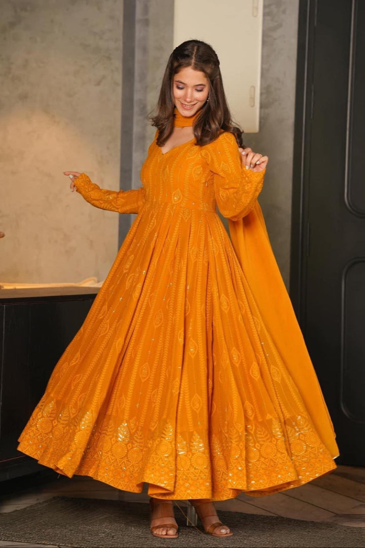 Woman wearing a mustard yellow dress with intricate patterns indoors.