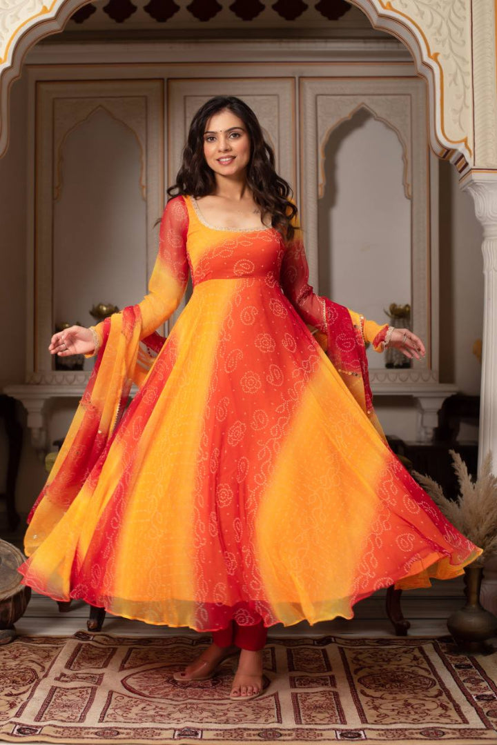 Woman in a vibrant orange and red traditional outfit standing in an ornate room.