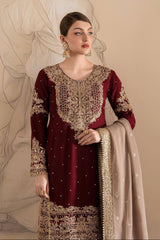Woman wearing a maroon and gold embroidered traditional outfit with a beige dupatta against a beige background.