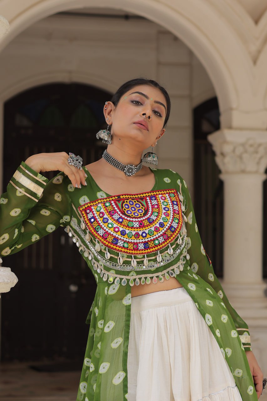 Woman in a green traditional outfit with colorful embellishments in an outdoor setting.