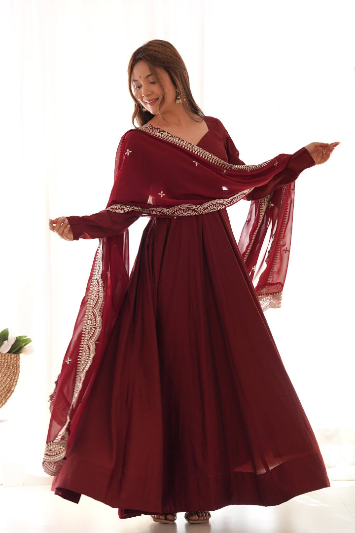 Woman wearing a burgundy dress with a sheer overlay against a white background