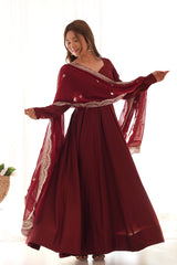 Woman wearing a burgundy dress with a sheer overlay against a white background