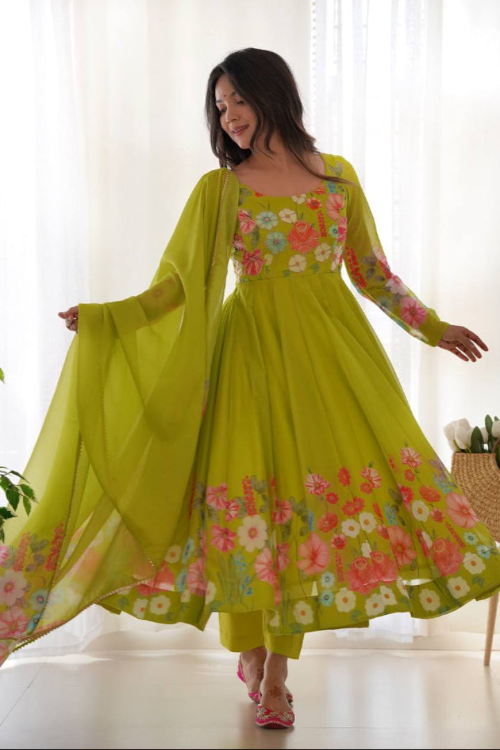 Woman wearing a bright green dress with floral patterns in a bright room.