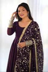 Woman wearing a purple traditional outfit with gold accents against a white background