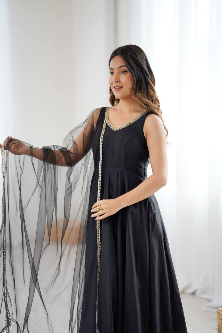 Woman wearing a black dress with sheer sleeves against a white background