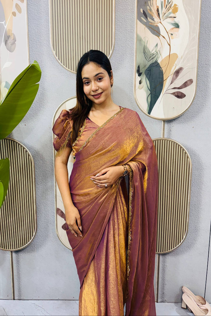 Woman in a maroon and gold saree standing against a decorative wall with abstract art.