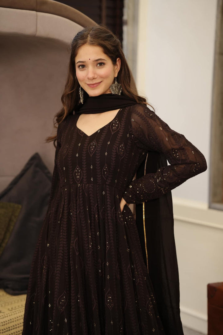 Woman wearing a dark brown traditional outfit indoors
