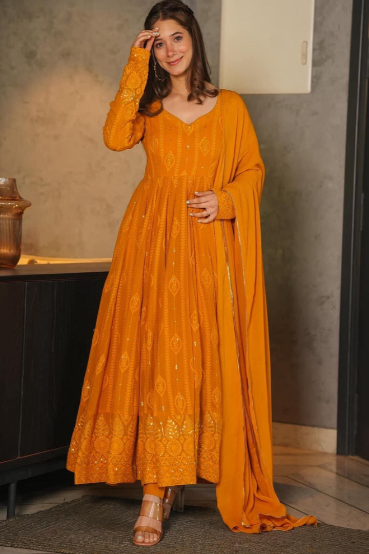 Woman wearing a mustard yellow dress with a matching dupatta indoors.