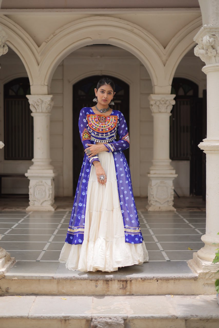 Woman in a blue and white traditional outfit standing in an architectural setting.