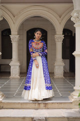 Woman in a blue and white traditional outfit standing in an architectural setting.