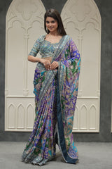 Woman wearing a colorful saree in front of decorative walls.