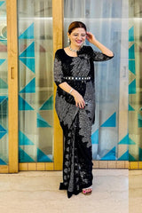Woman in a black and white patterned dress standing in front of a geometric-patterned glass door.