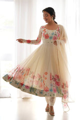 Woman wearing a floral dress with a sheer dupatta against a white curtain background