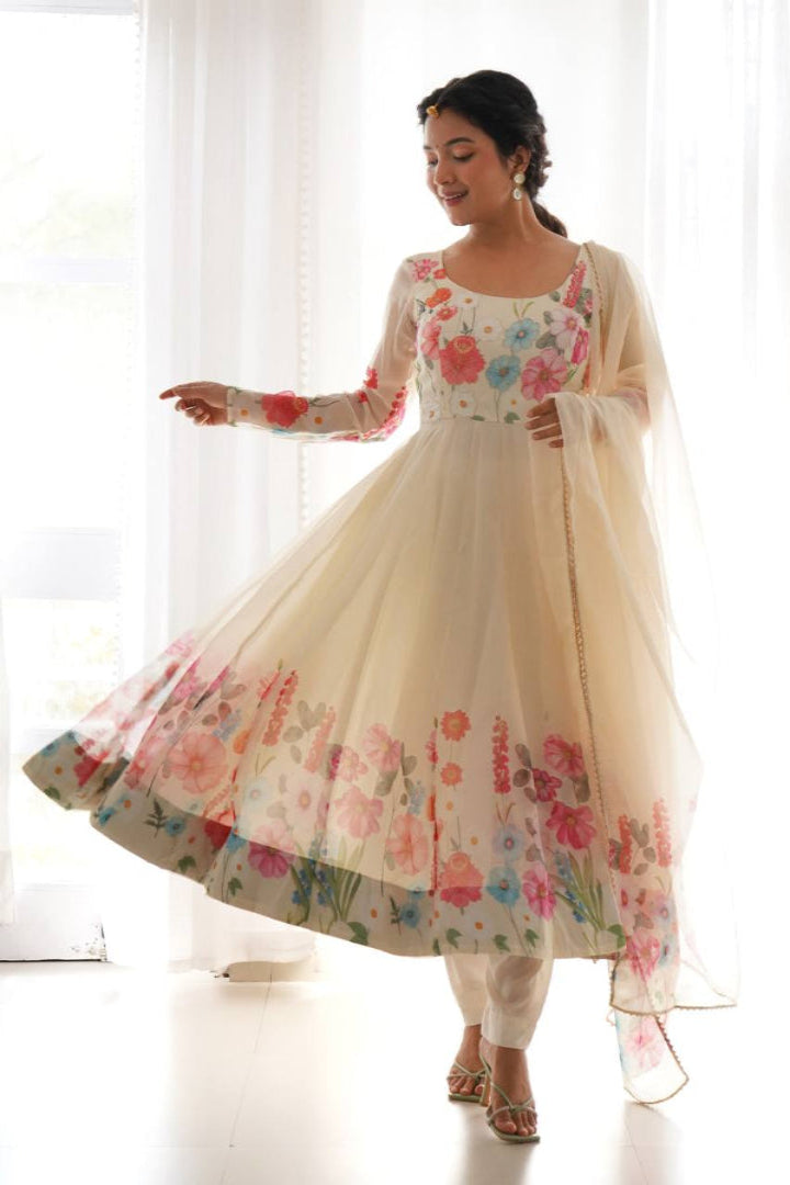 Woman wearing a floral dress with a sheer dupatta against a white curtain background