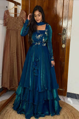 Woman wearing a blue floral dress standing next to a brown dress in a room.