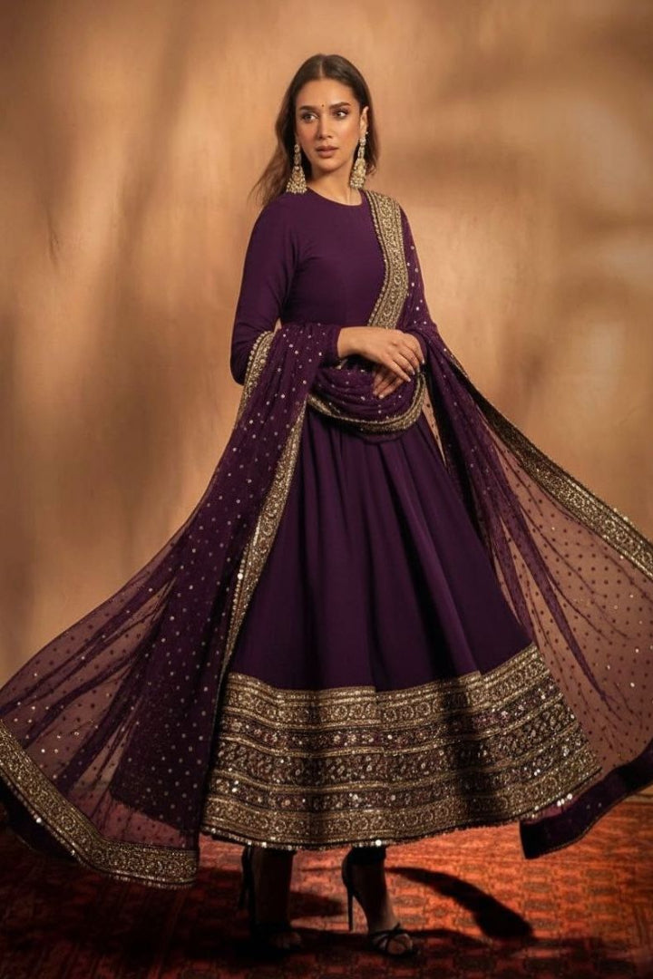 Woman wearing a purple traditional outfit with gold details on a brown background