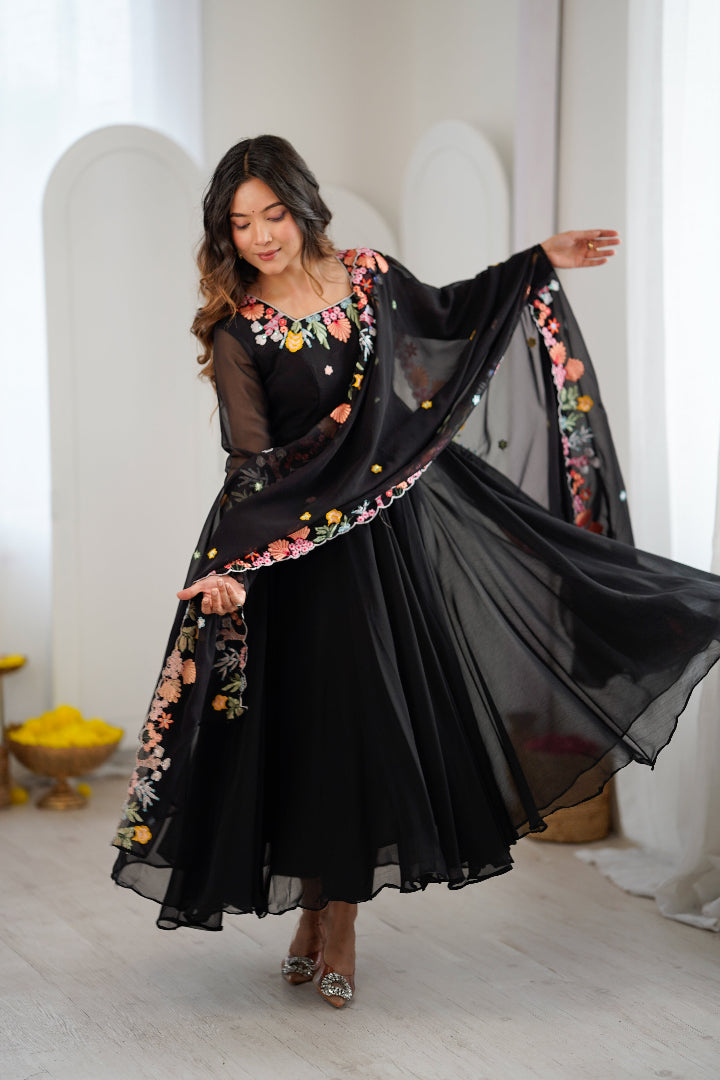 A woman modeling a black traditional-style dress with sheer sleeves and a matching dupatta