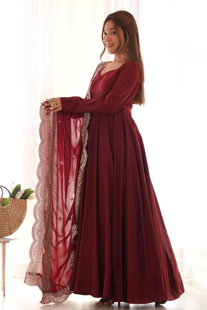 Woman wearing a burgundy dress with lace details, standing indoors.