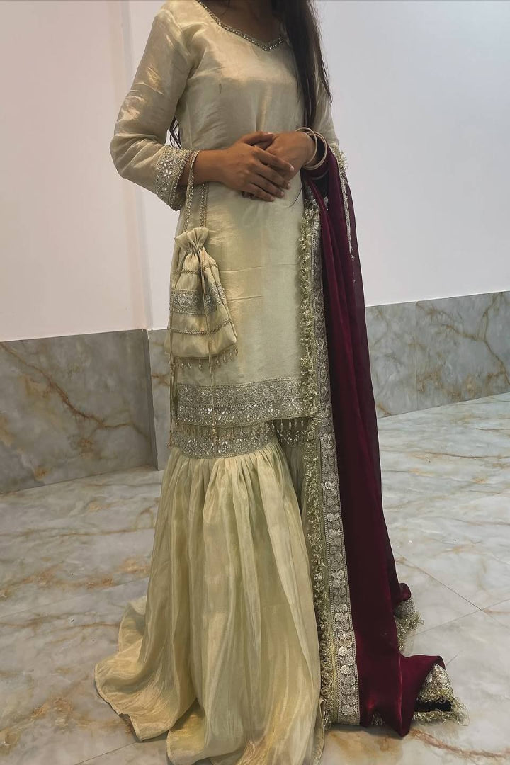 Traditional outfit with a gold and maroon color scheme on a marble floor.