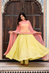 Woman in a yellow and pink traditional outfit standing in front of an ornate wooden door.