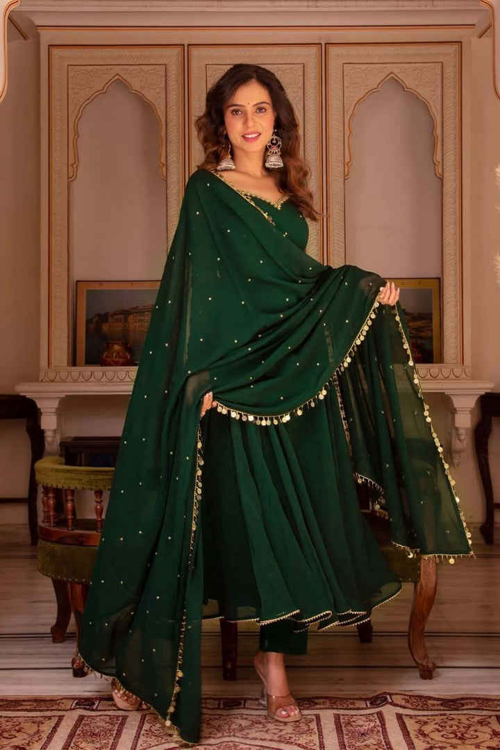 Woman in a green traditional outfit with gold details in an ornate room.