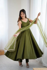 Woman wearing a green traditional outfit with a sheer dupatta in a bright room.