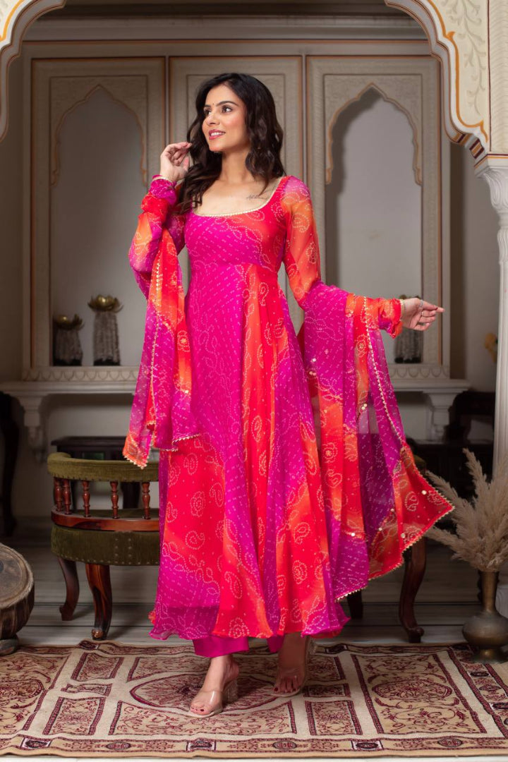 Woman wearing a vibrant pink and orange traditional outfit in an ornate room.