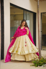 Woman in a traditional outfit with a pink dupatta standing outdoors.
