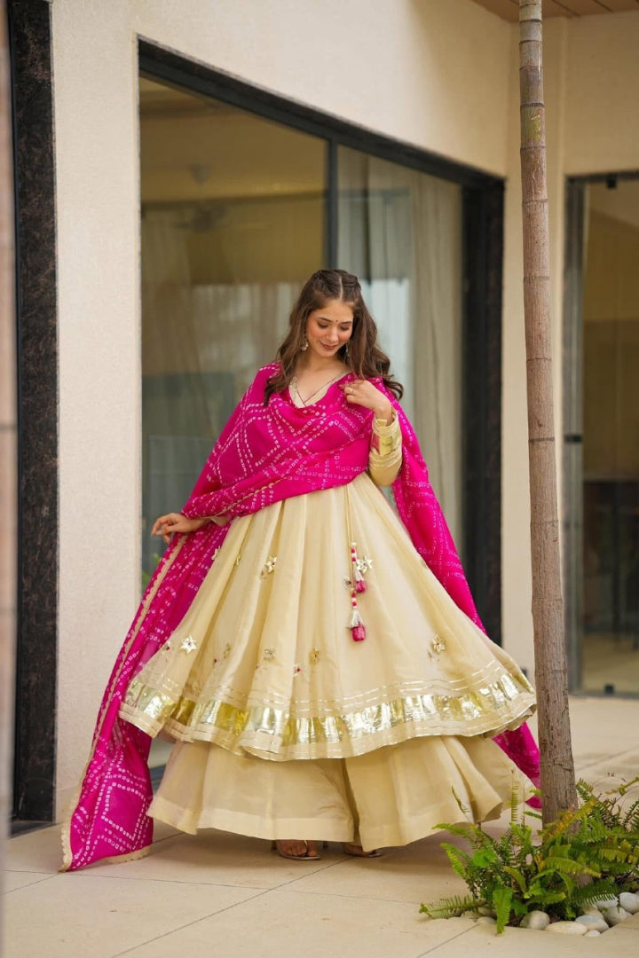 Woman in a traditional outfit with a pink dupatta standing outdoors.