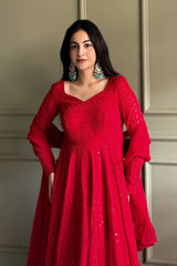 Woman wearing a red dress with intricate patterns against a neutral background
