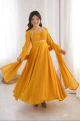 Woman wearing a yellow dress with long sleeves in a bright room.