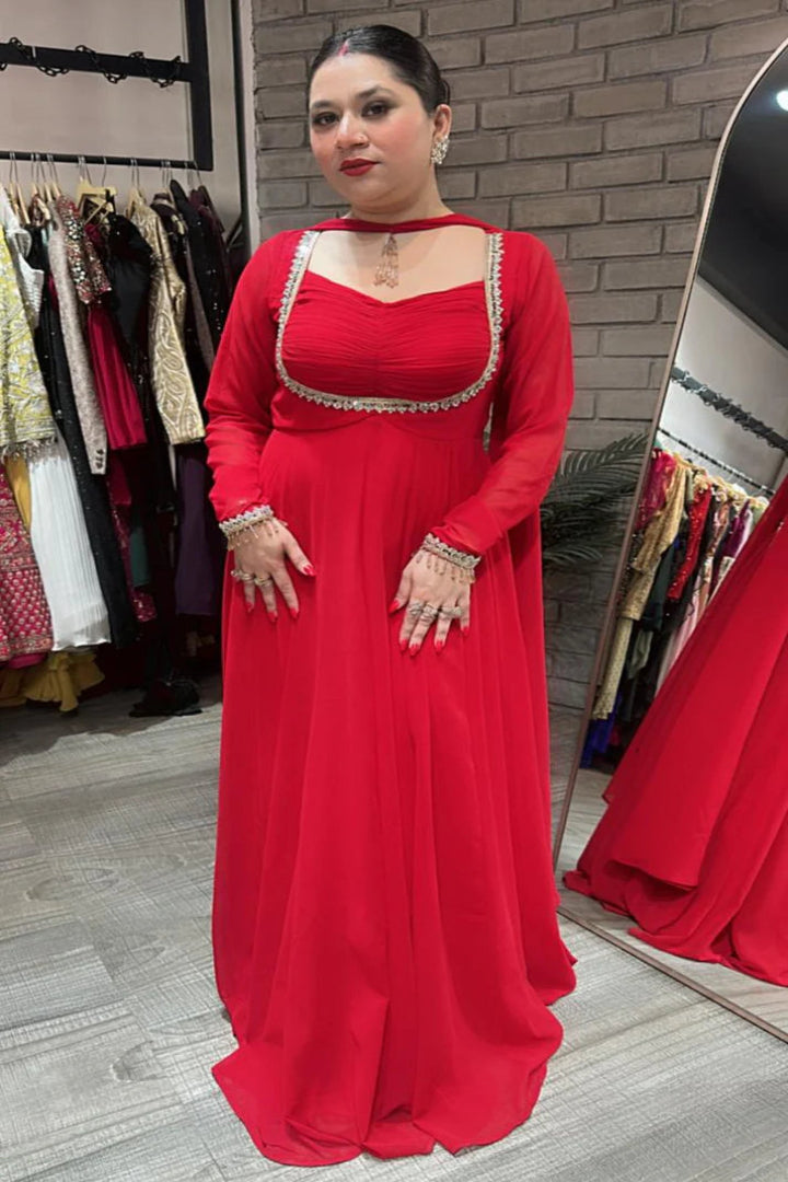 Woman wearing a red dress with gold detailing in a clothing store.