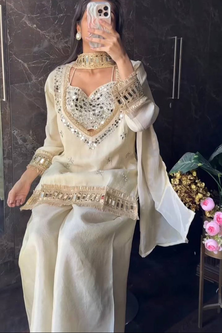 Person wearing a traditional outfit with intricate designs in a room with decorative elements.