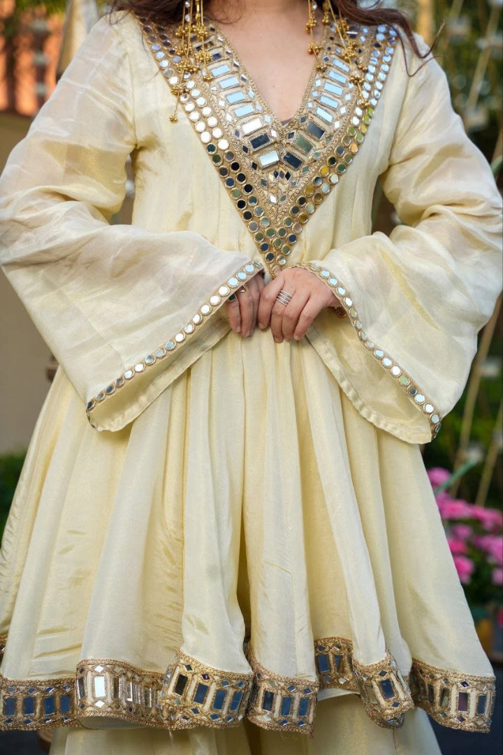 Light-colored traditional outfit with intricate embroidery and embellishments.