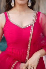 Close-up of a person wearing a bright pink traditional outfit with intricate detailing.