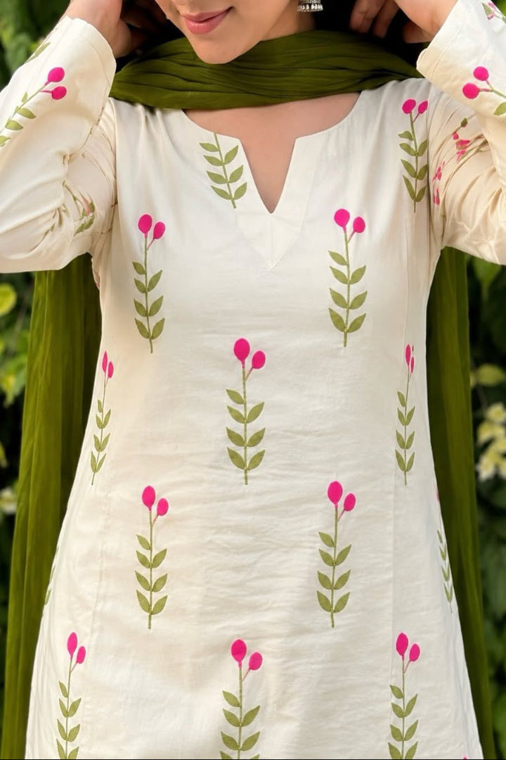 White kurta with floral patterns worn by a person against a green leafy background