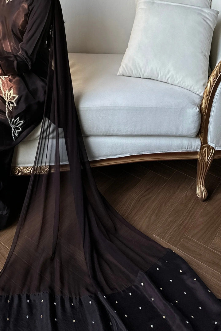 Black saree with white polka dots on a white sofa with gold accents