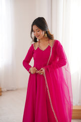 Woman wearing a bright pink traditional outfit with gold details indoors.