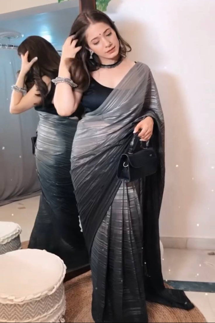 Woman in a silver saree standing in front of a mirror.