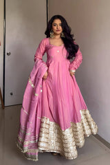 Woman in a pink traditional outfit with gold details against a neutral background