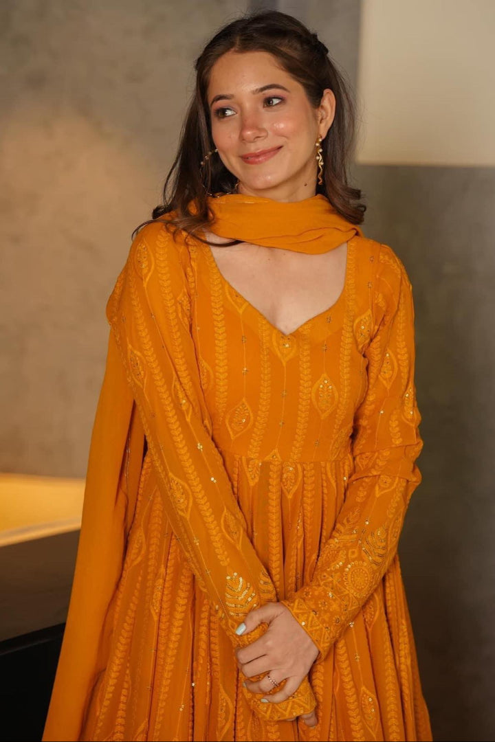 Woman wearing a mustard yellow dress with a textured pattern indoors.