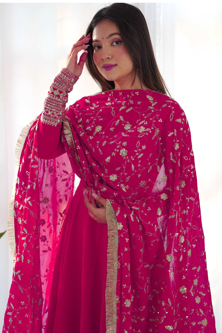 Woman wearing a bright pink traditional outfit with floral patterns on a white background