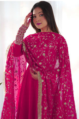 Woman wearing a bright pink traditional outfit with floral patterns on a white background