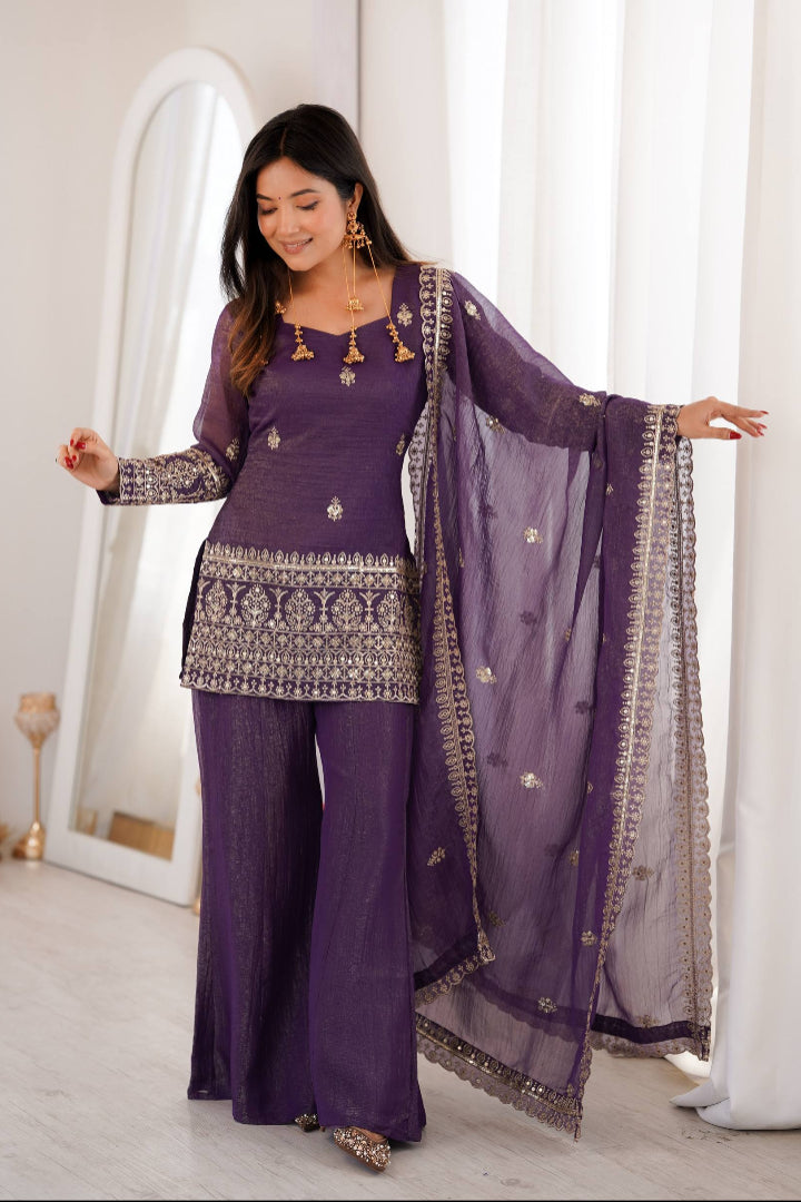 Woman wearing a purple traditional outfit with a matching dupatta in a well-lit room.