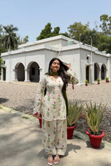 Woman in traditional outfit standing in front of a building with greenery