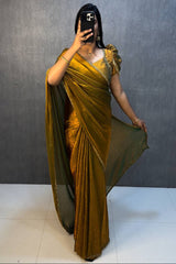Woman wearing a gold saree with a plain background