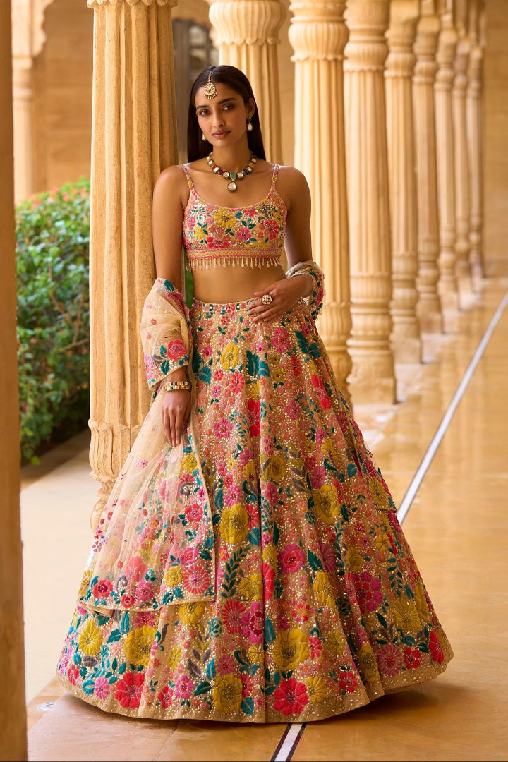 Woman in a colorful floral traditional outfit standing in a temple-like setting.