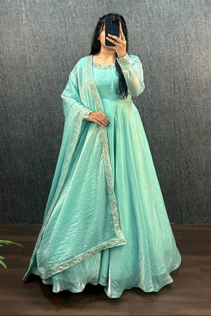 Person wearing a light blue traditional outfit with a matching dupatta against a dark background