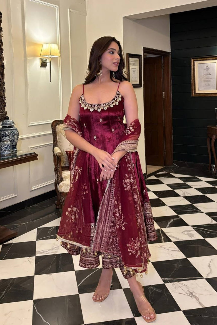 Woman in a red embroidered dress standing on a black and white checkered floor.